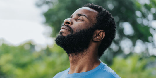 man standing outside breathing deeply with his eyes closed