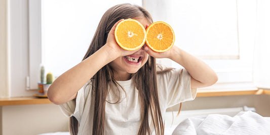 a little girl covering her eyes with orange slices