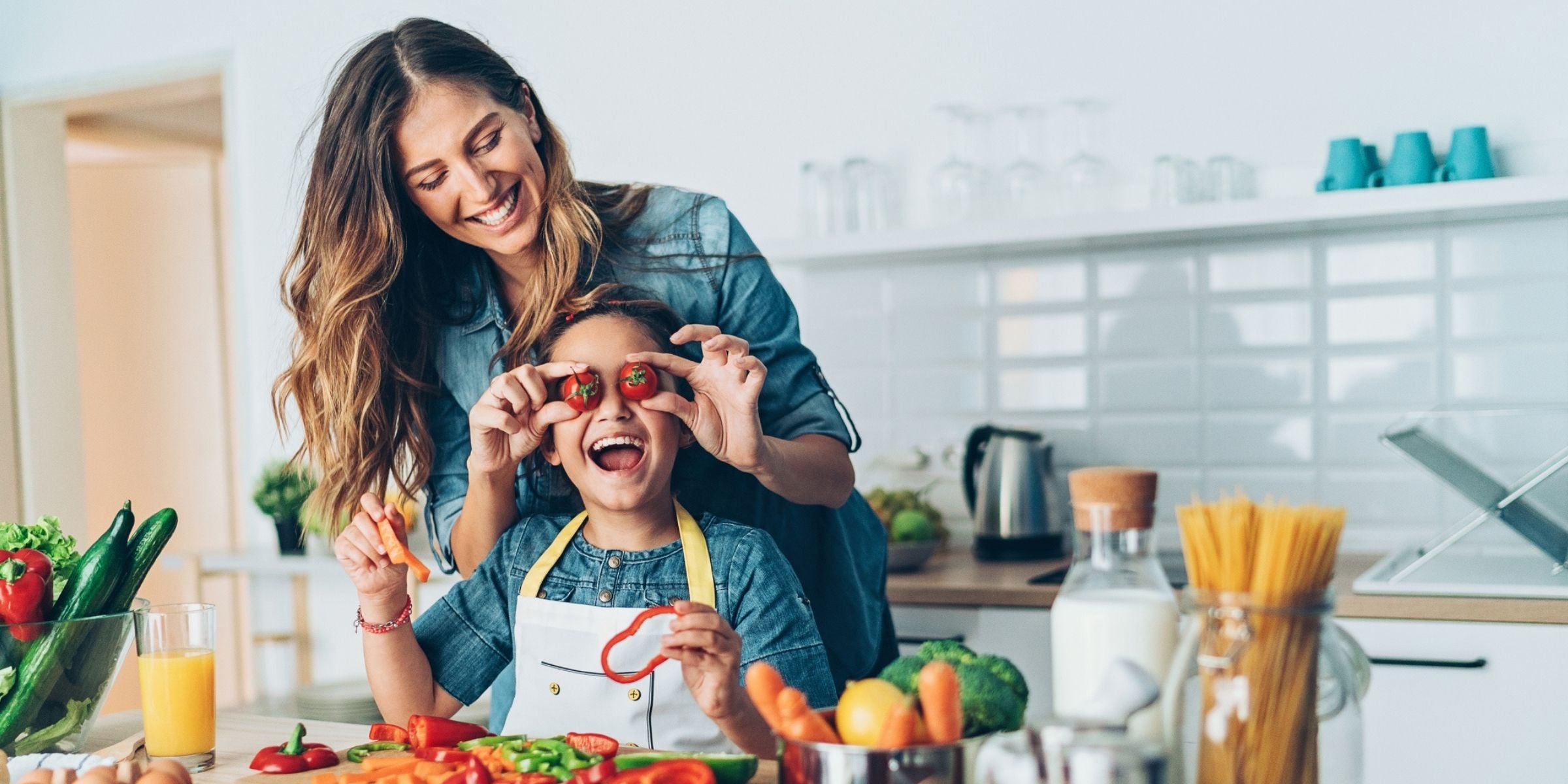 a mother and daughter smiling and cooking in the kitchen