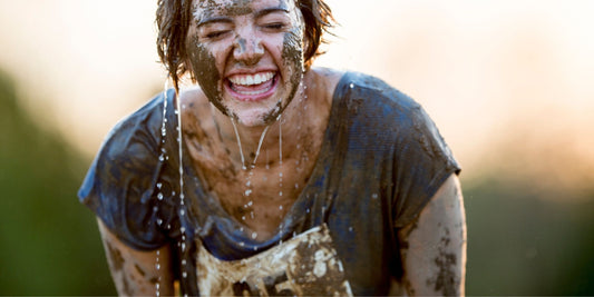a woman covered in water and mud laughing