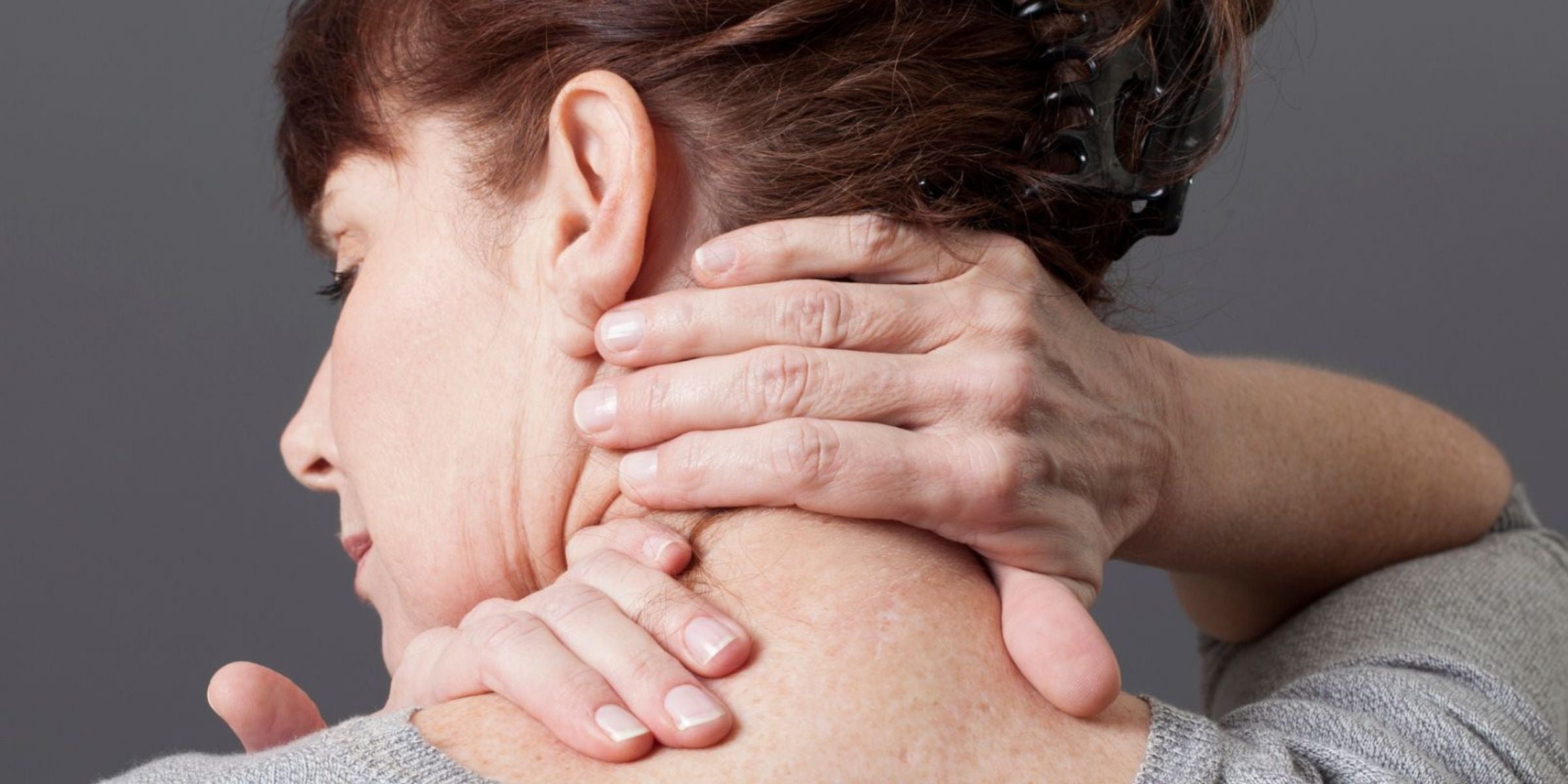 woman holding the back of her neck in pain