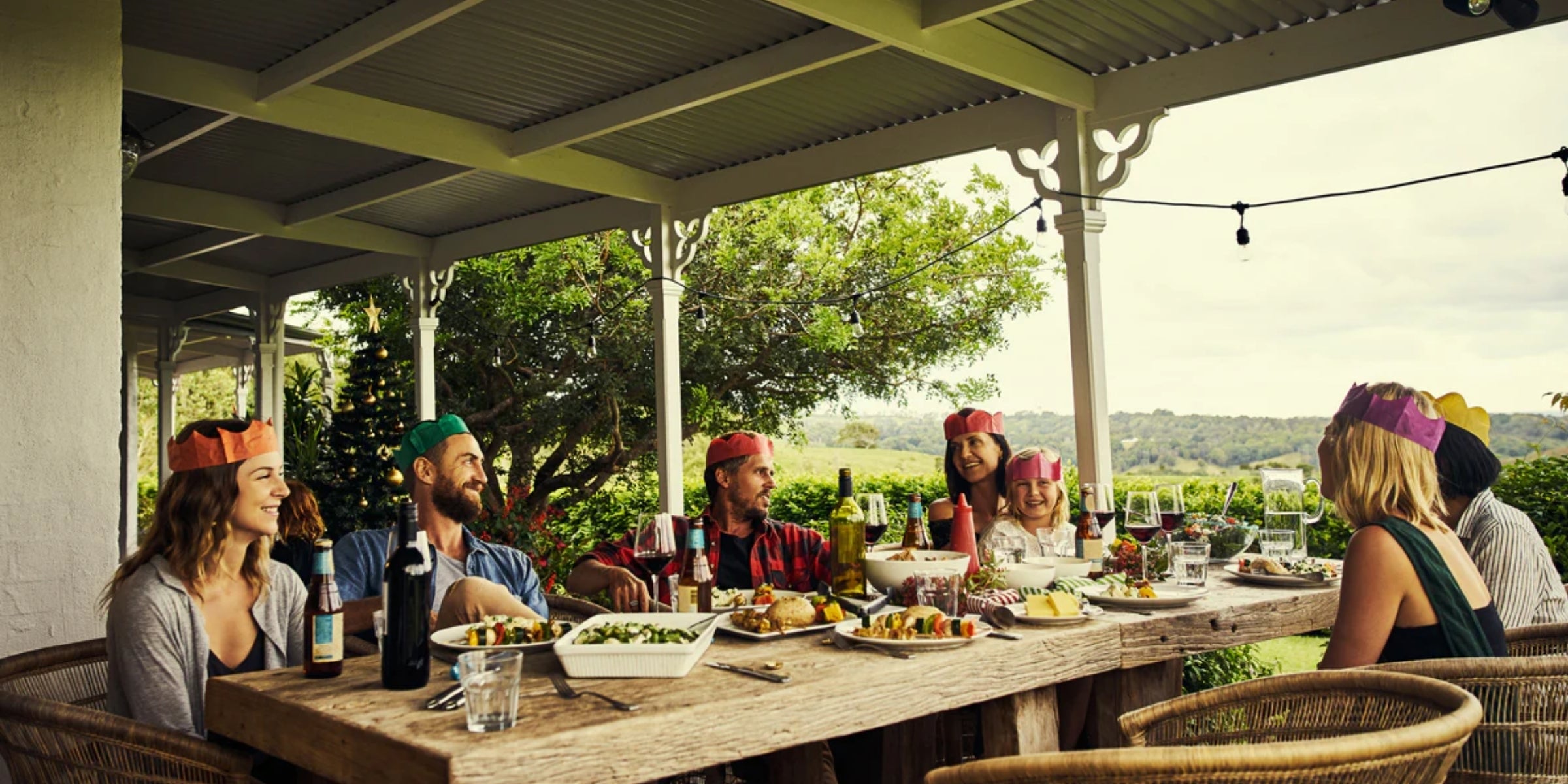 a group of people enjoying a meal outdoors on a patio with a scenic view of greenery in the background