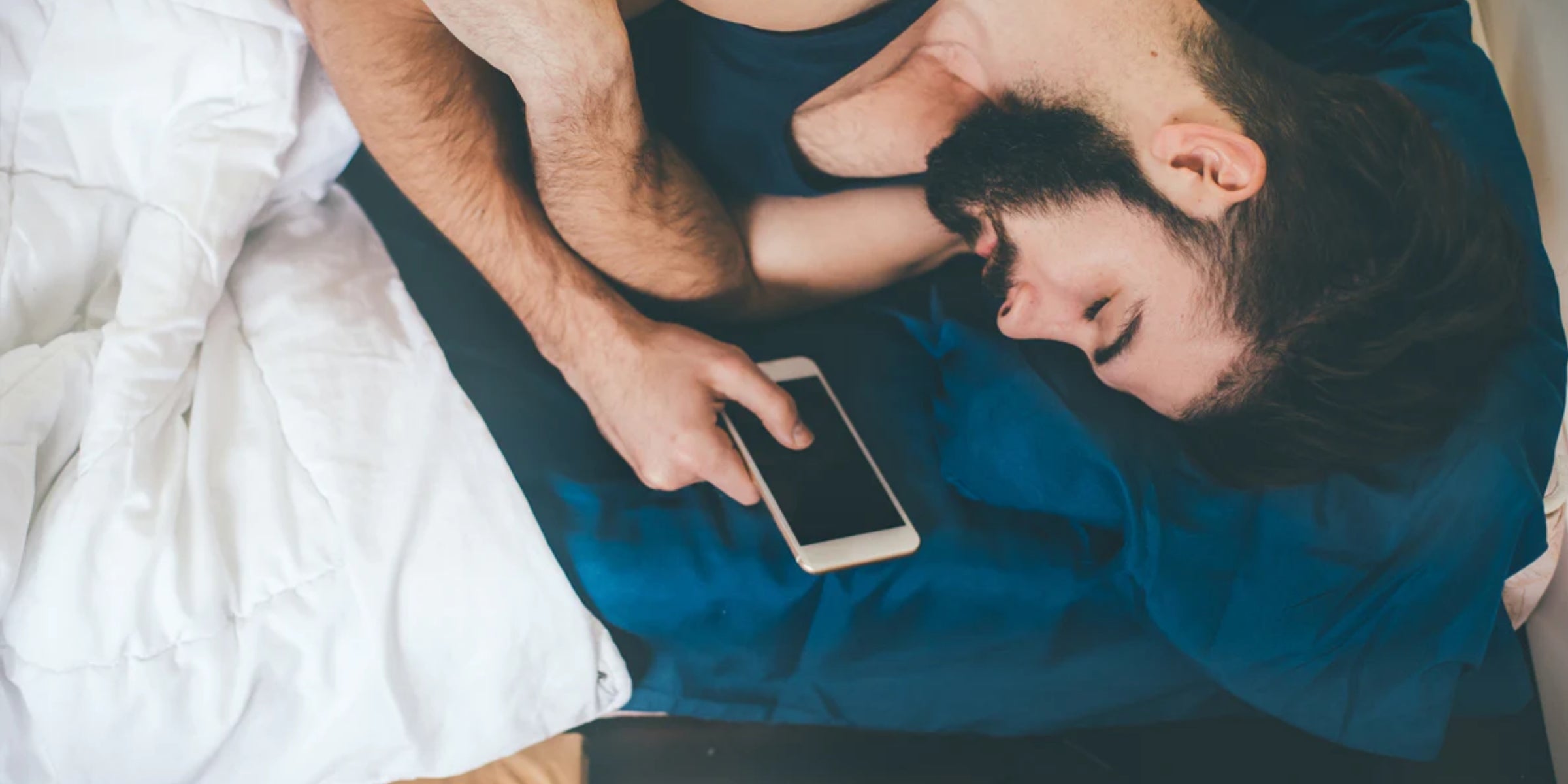 a person lying in bed, holding a smartphone