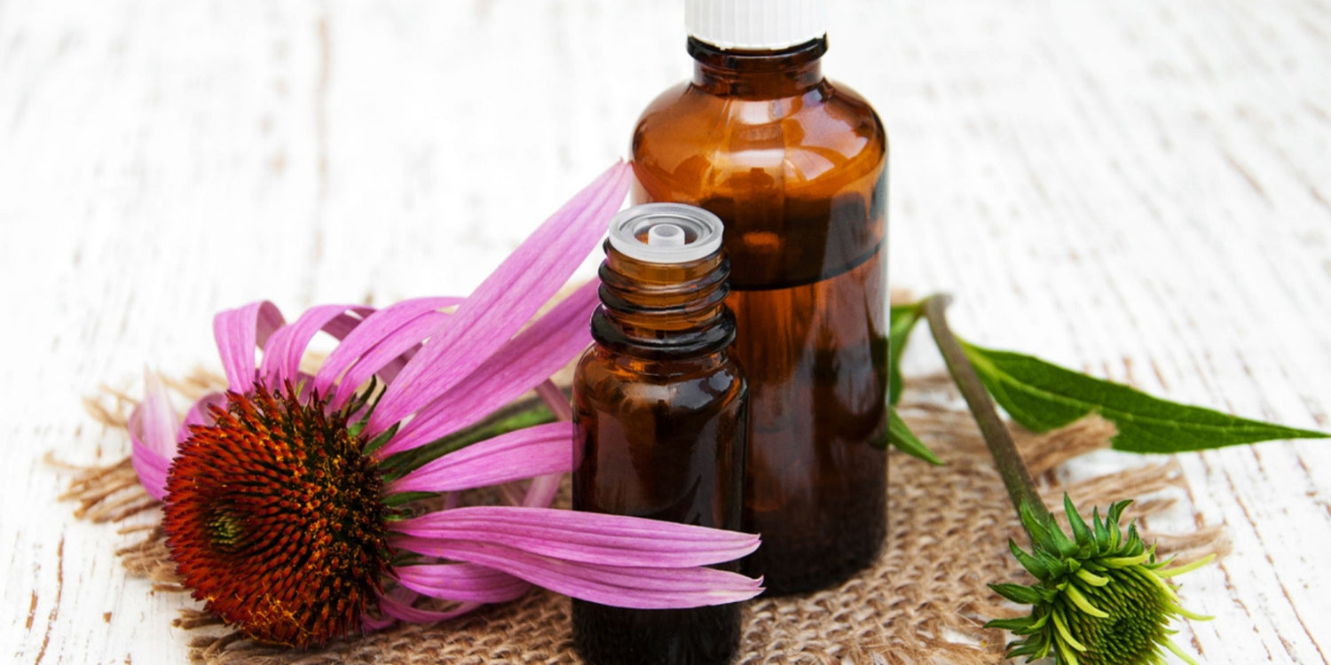 a brown glass bottle of essential oil with its cap removed with a vibrant purple flower