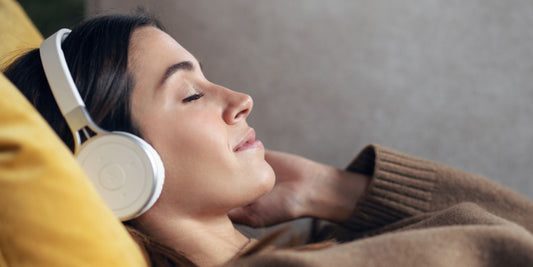 a woman lying back closing her eyes while listening to music through headphones