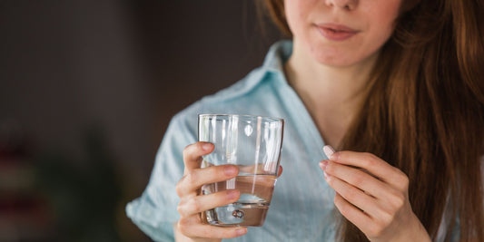 a woman taking a tablet with a glass of water